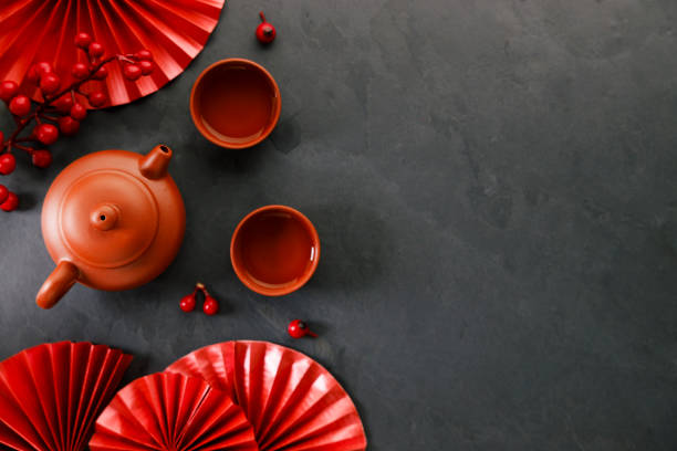Chinese new year festival decorations with classic clay teapot and red Chinese folded fans. Chinese new year festival decorations with classic clay teapot and red Chinese folded fans on dark background. Celebrate Happy Chinese new year background concept. Top view. mandarin chinese new year stock pictures, royalty-free photos & images