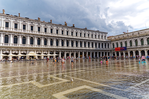 Tourists at famous flooded square Piazza San Marco at City of Venice on a cloudy summer day. Photo taken August 6th, 2023, Venice, Italy.