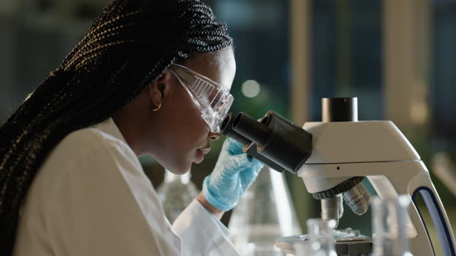 Research, microscope and black woman in laboratory at night for medical analysis, science and study. Healthcare, biotechnology and scientist with equipment for sample, medicine or vaccine development