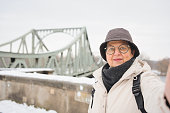Older tourist taking a selfie on the Glienicker Bridge in Potsdam, Berlin, Germany. Winter holiday concept and travelling lifestyle.