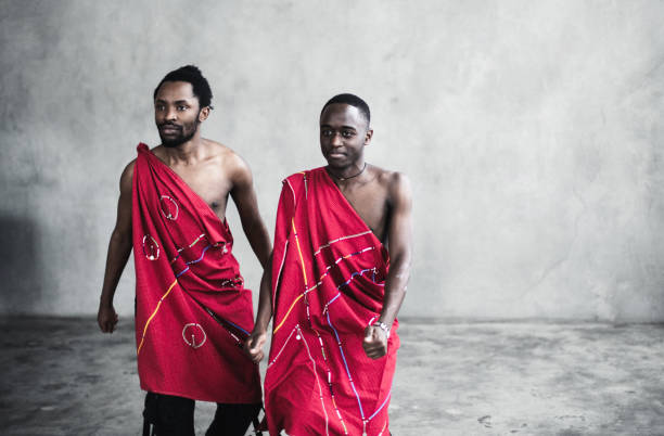 Two black young men in traditional costumes dancing in an empty room