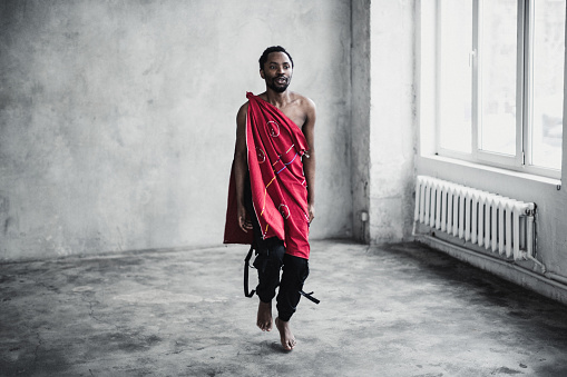 Young black men in traditional costumes dancing in an empty room