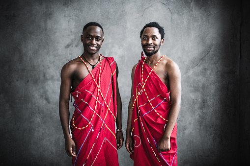 Portrait of beautiful african young men in traditional costumes against dark concrete wall