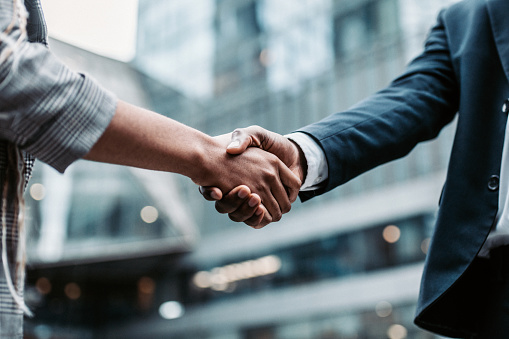 Meeting success. Two business persons shaking hands standing outside