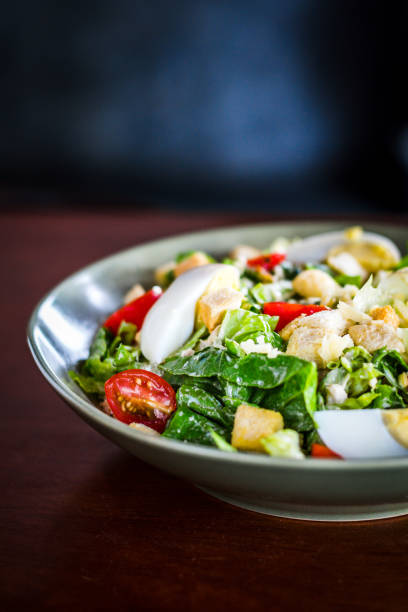 caesar salad of 
lettuce, grilled chicken breast, croutons, boiled egg, cherry tomatoes served in a bowl - salad caesar salad main course restaurant foto e immagini stock