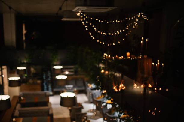 istock Restaurant interior with blurred bokeh from garlands and lamps. Abstract blur restaurant at night for background usage. Blur background luxury cafe. Top view of a cozy cafe in the evening. 1916751704