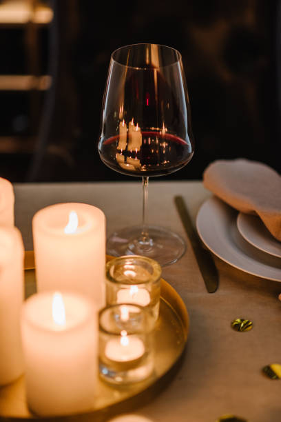 istock Wine glass, details table set, Valentine's Day evening. Romantic dinner at home at night. Candlelight luxury date in restaurant. Plates, cutlery, napkin, golden decor, garland. Table setting for event 1916752239