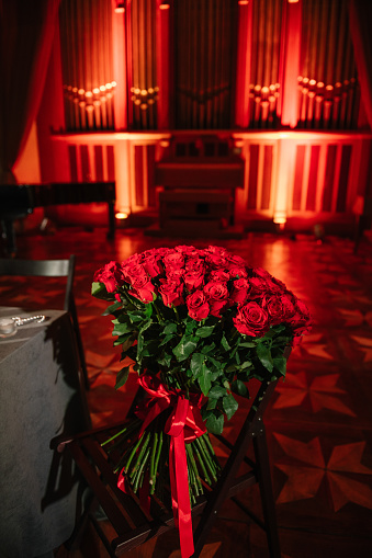 A large bouquet of red roses for surprise congratulates in the organ hall. Luxury romantic date. Candlelight for couple on Valentine's day. Location for surprise marriage proposal at night.