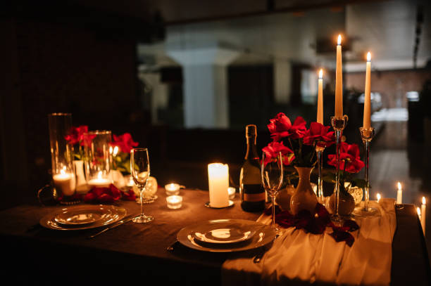 istock Romantic dinner setup at night. Champagne glasses, flowers. Table setting for a couple, Valentine's Day evening, burning candles for a surprise marriage proposal. Candle light date in a restaurant. 1916752258
