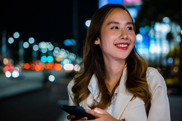 istock Young woman using modern smartphone in night city 1916760072