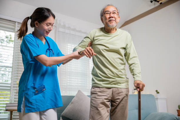 istock Young carer supporting helping senior man stand up with walking stick from sofa 1916760093