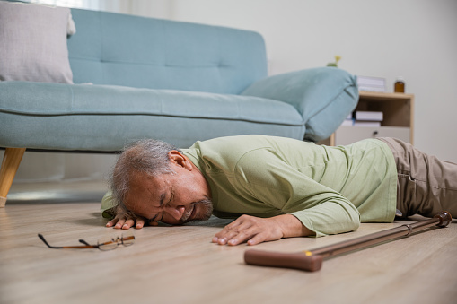 Older senior man headache lying on the floor after falling down he pain and hurt from osteoporosis, Elderly man falling on the floor alone with walking stick at home, Health care and medicine