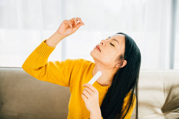 istock Woman at home uses a rapid antigen test kit inserting a swab into her nose 1916760500