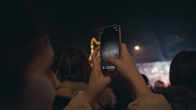Closeup of Hands of Young Woman with Crowd Filming Music Concert with Smartphone