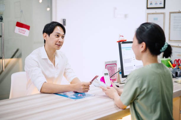 asian chinese male using credit card to make payment in dental clinic. - dentist office built structure doctors office retail - fotografias e filmes do acervo