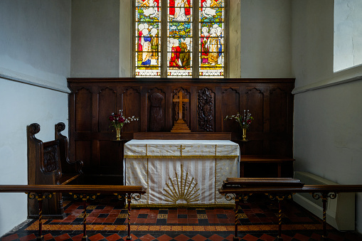 Interior of All Saints Church with altar, crucifix and stained glass window.