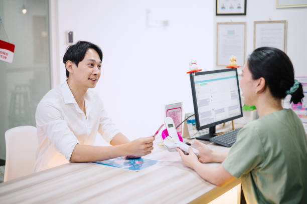 asian chinese male using credit card to make payment in dental clinic. - dentist office built structure doctors office retail - fotografias e filmes do acervo