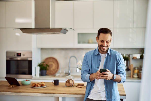 istock A smiling male remote sales representative texting with his colleagues on his cellphone in a kitchen setting. 1916796487