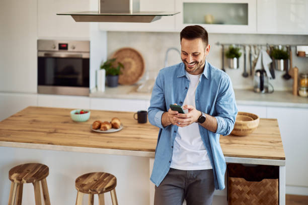 istock A smiling freelance man sending his coworker a funny text message while standing in a kitchen. 1916797588