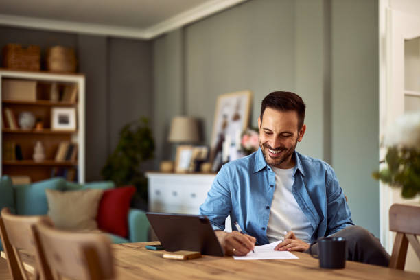 istock A cheerful young adult man interviewing a candidate over an online platform on a tablet while writing notes on a sheet of paper in front of him. 1916798652