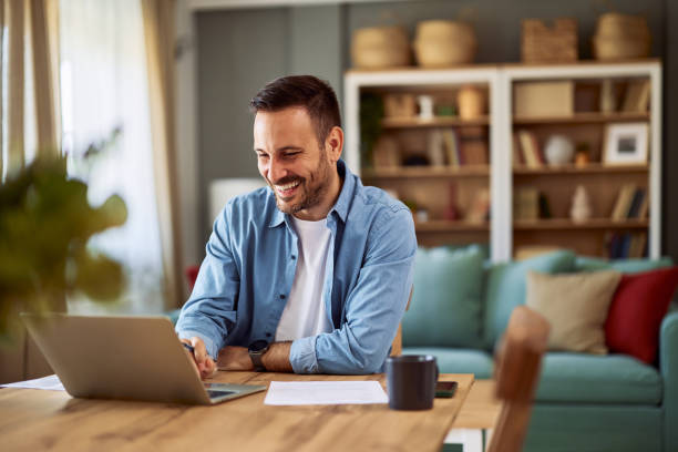 istock A cheerful male online assistant using his laptop for work while sitting at a table in a home office. 1916804573