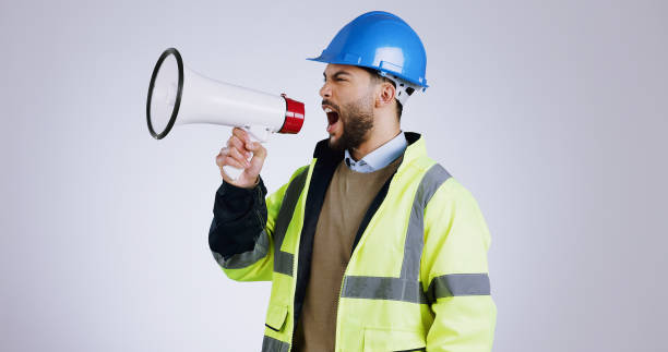 istock Construction, angry man and megaphone for shouting in studio with mock up on white background in Mexico. Person, engineer or manager with frustrated face for loudspeaker, workplace and instruction 1916805099