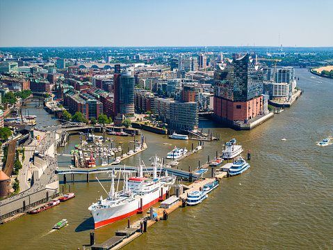 Amsterdam, Netherlands: Amsterdam Centraal train station in the distance with a canal and boats in the foreground. Copy space available in the white sky.