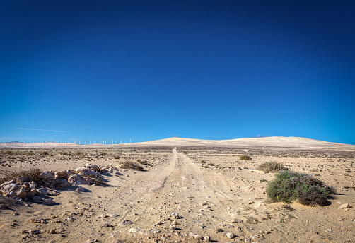 A deserted dirt road in a barren desert landscape, with no sign of life in sight