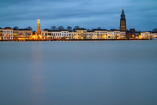 Zutphen skyline at the river IJssel with high water level after heavy rainfall upstream in December 2023. Evening view photo with long exposure giving the river a smooth surface.