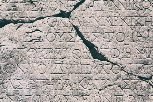 Retro text background. Fragment of broken ancient inscription (imperial law in ancient Greek language), carved on marble block. Monochrome. Sagalassos Ancient city, Turkey (Turkiye)