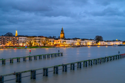 Zutphen skyline at the river IJssel with high water level after heavy rainfall upstream in December 2023. Evening view photo with long exposure giving the river a smooth surface.