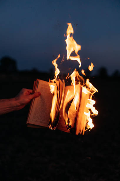 istock Burning Knowledge: Hand Holding a Book Engulfed in Flames 1916844137