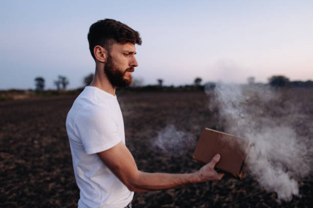 This dramatic image captures a man holding a burning book in his hands, symbolizing powerful themes such as transformation, protest, or the impact of knowledge. The flames add a sense of intensity and urgency to the scene.