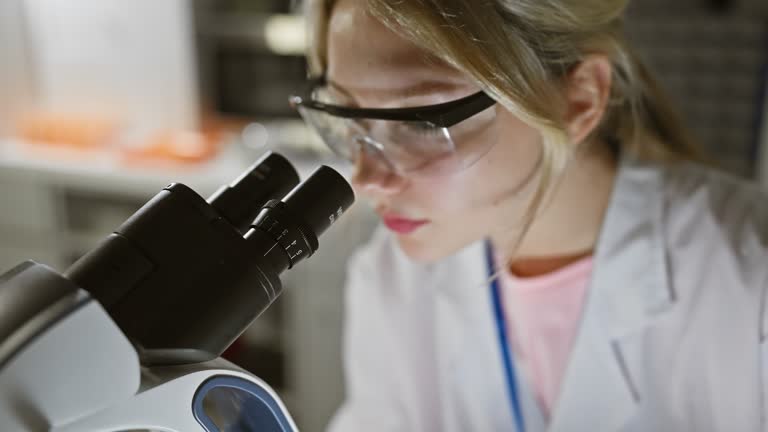 Focused woman scientist using microscope in laboratory setting