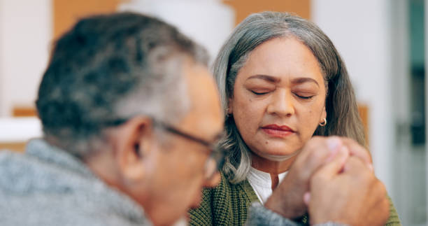 istock Hope, holding hands or old couple praying for support, trust or faith in marriage commitment at home. Eyes closed, wellness or senior man bonding with an elderly woman in prayer for peace or worship 1916911476