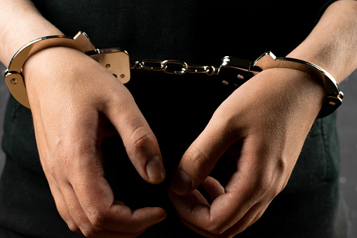 Male hands handcuffed in close-up. The arrested criminal. Crime and the law.