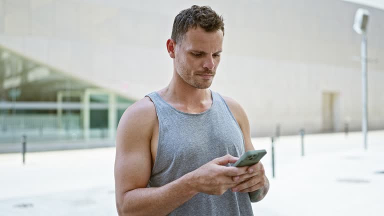 Handsome man using smartphone on sunny urban street.