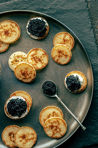 Blinis with black caviar and cream cheese, shot from above, mini pancakes, an elegant appetizer