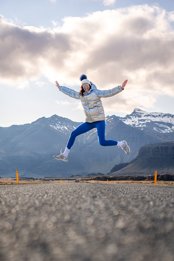 A young female skateboarder executing an airborne trick, jumping joyfully in the air with her board