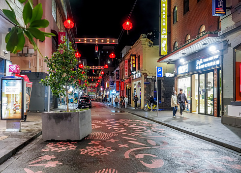Melbourne, Australia - Aug 29, 2022: Night view of Chinatown (Little Bourke Street). Feature traditional street red lanterns. Shops and pedestrians line both sides of the narrow street.