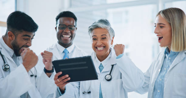 istock Doctors, teamwork and celebration on tablet for hospital results, healthcare solution and reading report with mentor. Professional medical group of people on digital technology for winning or success 1916920047
