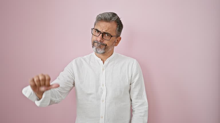 Handsome young hispanic man, a grey-haired scientist engrossed in research on his computer, sitting alone. a splash of pink background adds color to his world of science.