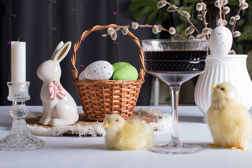 An Easter basket with colored eggs and an Easter bunny. A bouquet of fluffy willow in a vase