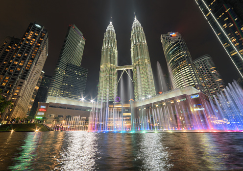 Kuala Lumpur, Malaysia - 21 June, 2023: Evening view of the Petronas Twin Towers and colorful fountains on Lake Symphony at the KLCC Park. The Petronas Towers are a popular tourist attraction of Asia.