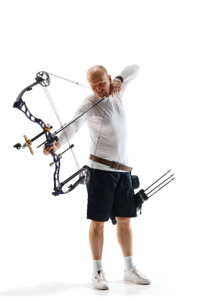 istock Concentrated man, archery athlete with special equipment training, aiming archery bow on target isolated over white studio background. Archery sport, competition 1916986433