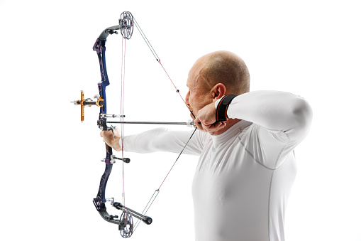 Man, professional archer training, aiming archery bow into target isolated over white studio background. Concept of professional sport and hobby, competition, action, game
