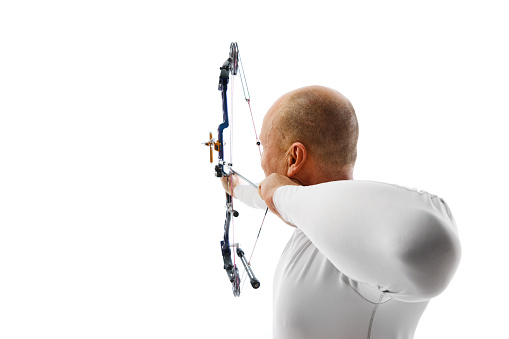 Back view image of man, archery at hele aiming with archery bow on target isolated over white studio background. Concept of professional sport and hobby, competition, action, game