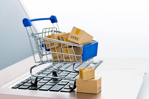 Shopping cart with small boxes on laptop keyboard.