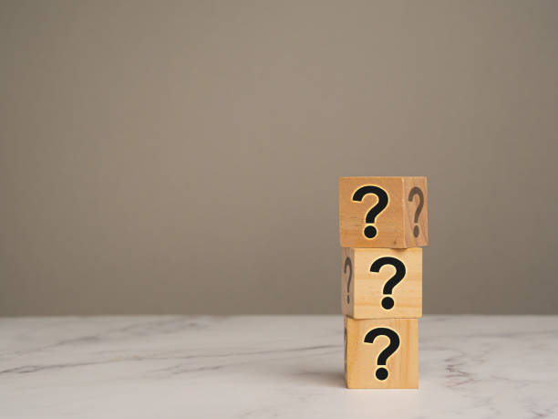 istock Wooden cubes stacked with question mark symbols on a marble table with a gray background. 1917002008