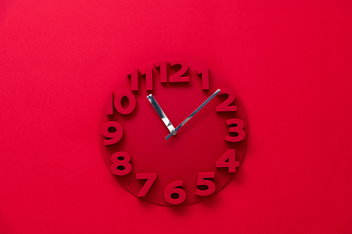 Red alarm clock isolated on white background shows seven o clock in the morning time to get up to wake up and have breakfast morning or evening run to go to work 7 am pm.